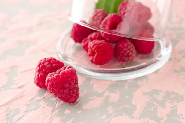 Glass cup and sweet ripe raspberry on color background — Stock Photo, Image