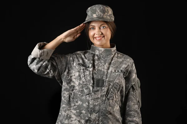 Saluting żeński żołnierz na ciemnym tle — Zdjęcie stockowe