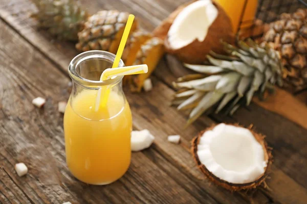 Botella de jugo de piña fresca y coco sobre mesa de madera — Foto de Stock