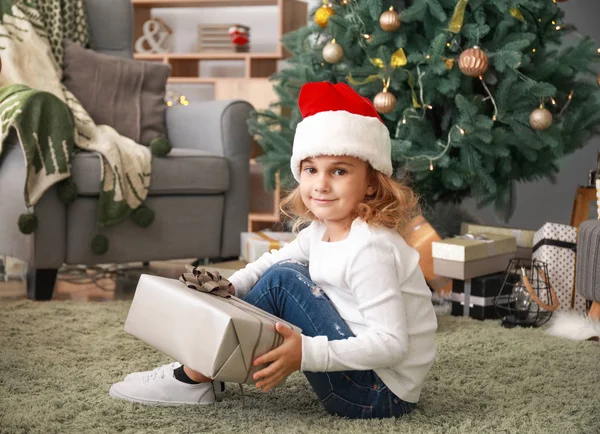 Nettes kleines Mädchen mit Weihnachtsgeschenk zu Hause — Stockfoto