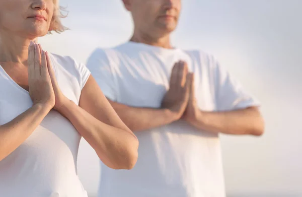 Mature couple practicing yoga at sea resort — Stock Photo, Image