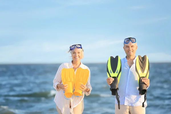Счастливая зрелая пара с масками и веслами для подводного плавания, веселящиеся на морском курорте — стоковое фото
