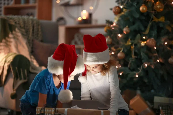 Happy children opening Christmas gifts in evening — Stock Photo, Image