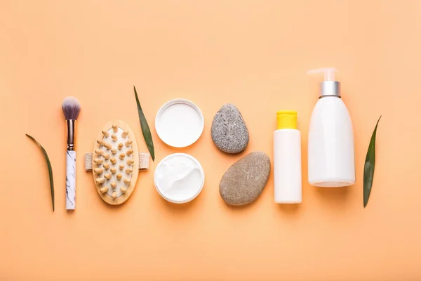 Set of cosmetic products, massage brush and spa stones on color background — Stock Photo, Image