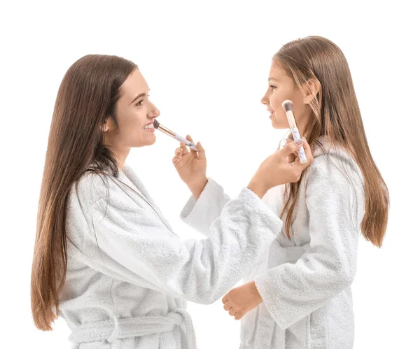 Mutter und ihre kleine Tochter im Bademantel schminken sich vor weißem Hintergrund — Stockfoto