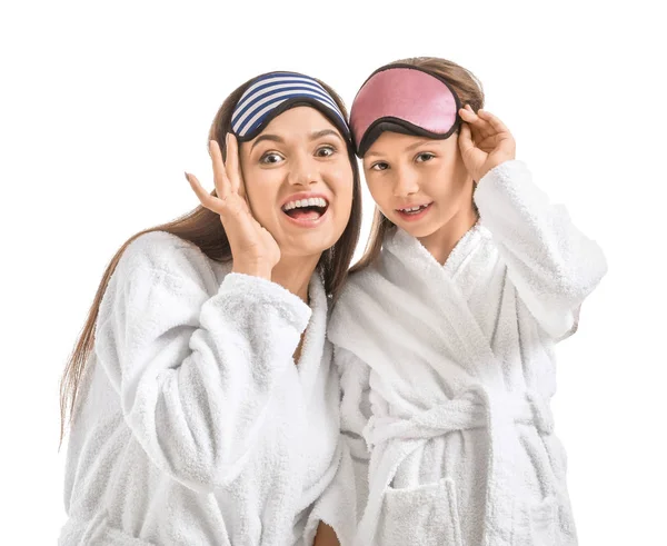 Mother and her little daughter in bathrobes and with sleep masks on white background — Stock Photo, Image