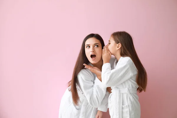 Niña diciéndole a madre su secreto sobre el fondo de color — Foto de Stock