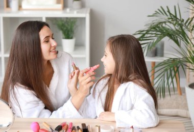 Anne ve bornozlu küçük kızı evde makyaj yapıyor