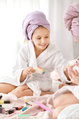 Anne ve bornoz küçük kızı yatak odasında çivi manikür