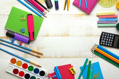 Okul malzemelerinden yapılmış çerçeve beyaz ahşap arka planda