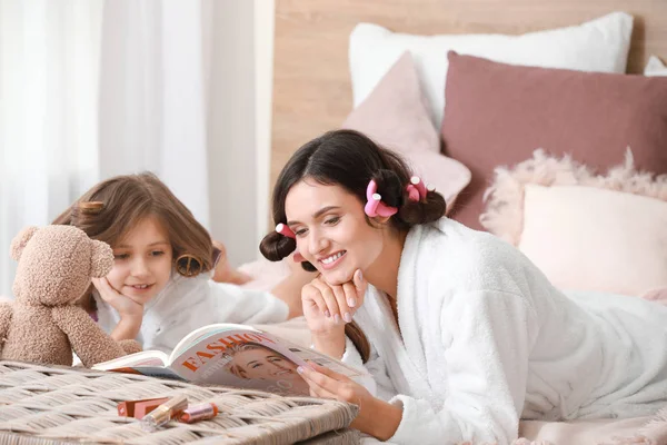 Mother and her little daughter in bathrobes and with fashion magazine relaxing at home — Stock Photo, Image