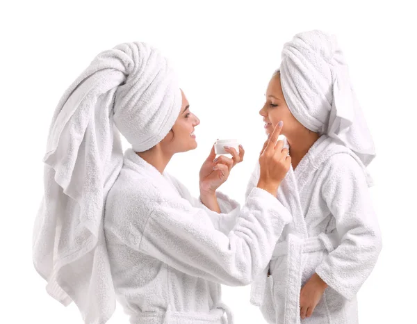 Mother applying cream on face of her little daughter against white background — Stock Photo, Image