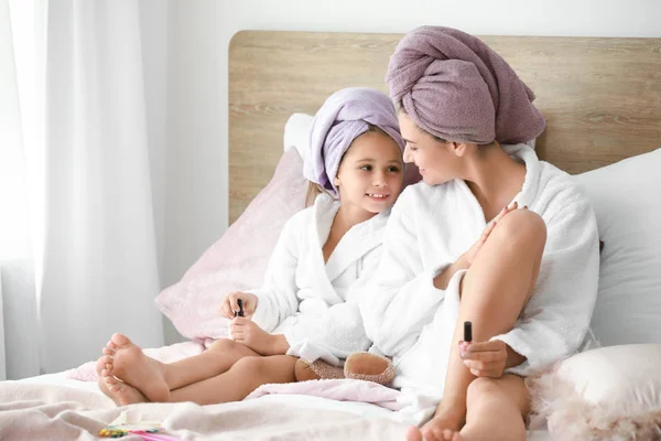 Mutter und ihre kleine Tochter in Bademänteln bei Pediküre im Schlafzimmer — Stockfoto