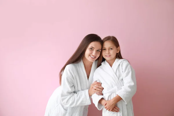 Mutter und ihre kleine Tochter in Bademänteln vor farbigem Hintergrund — Stockfoto