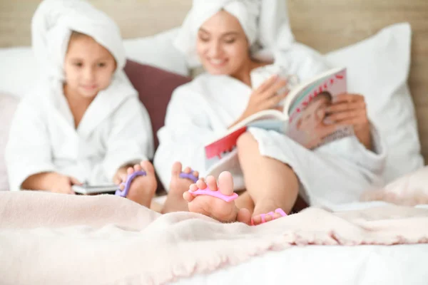 Mother and her little daughter in bathrobes doing pedicure at home — Stock Photo, Image