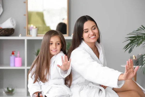 Mutter und ihre kleine Tochter in Bademänteln beim Nägelmachen zu Hause — Stockfoto