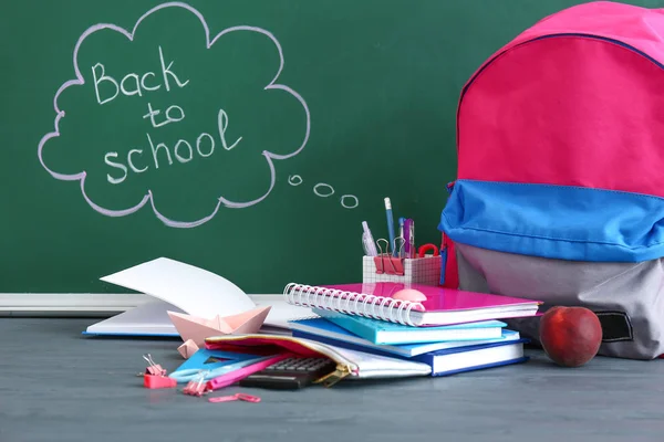 Uppsättning skolmaterial med ryggsäck på bordet i Classroom — Stockfoto