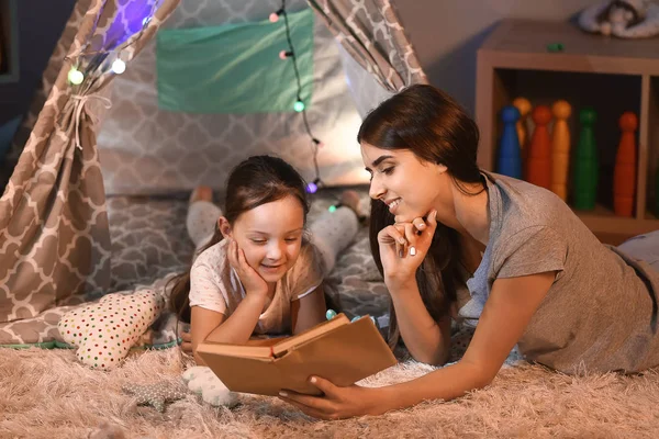Mother and her little daughter reading book in evening — Stock Photo, Image