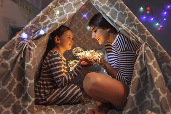 Mamma och hennes lilla dotter med Fairy Lights på kvällen hemma — Stockfoto