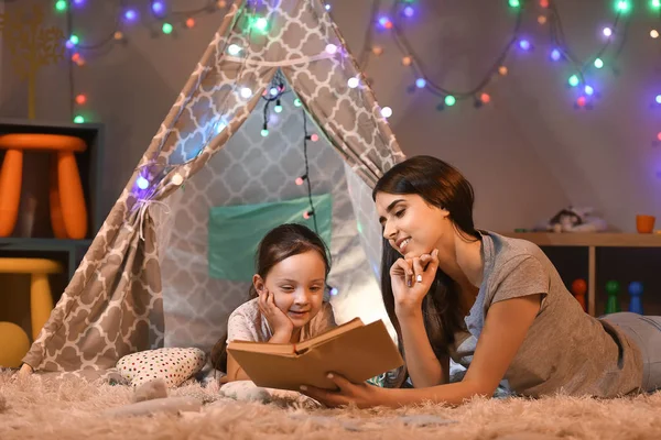 Mor och hennes lilla dotter läsning bok på kvällen — Stockfoto