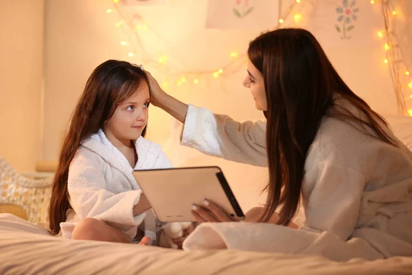 Woman and her cute little daughter with tablet computer in bedroom — Stock Photo, Image