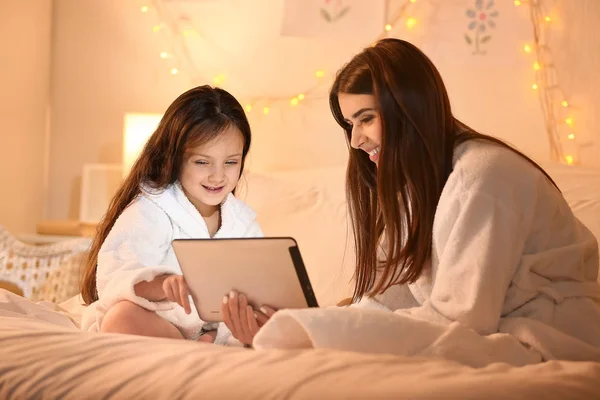 Woman and her cute little daughter with tablet computer in bedroom — Stock Photo, Image