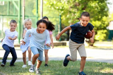 Sevimli küçük çocuklar parkta rugby topu ile oynuyor