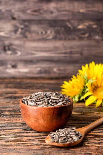 Cuenco y cuchara con semillas de girasol sobre mesa de madera —  Fotos de Stock