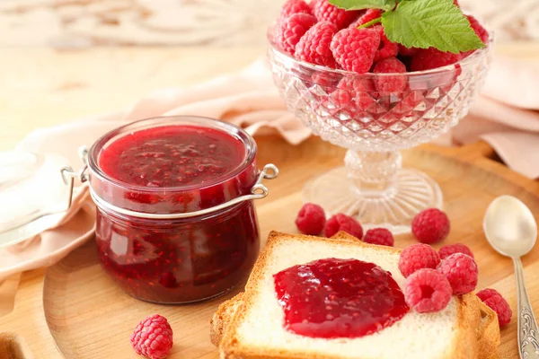 Confiture de framboises savoureuse avec pain frais sur planche de bois — Photo