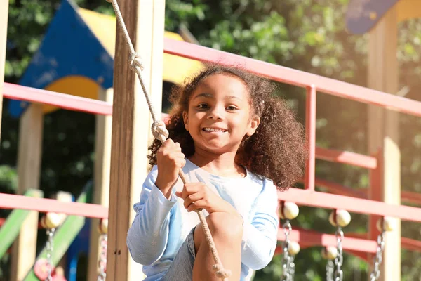 Cute African-American girl having fun on playground outdoors — Stock Photo, Image
