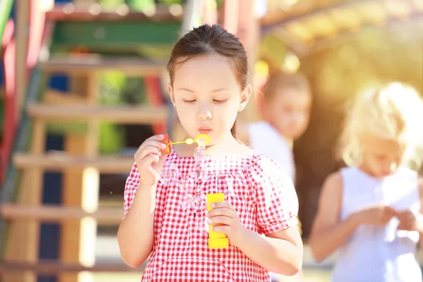 Cute girl blowing soap bubbles outdoors — Stock Photo, Image