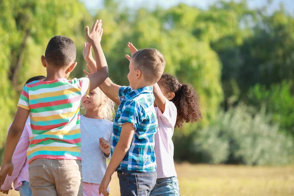 Grupo de niños pequeños que se dan choca los cinco al aire libre — Foto de Stock