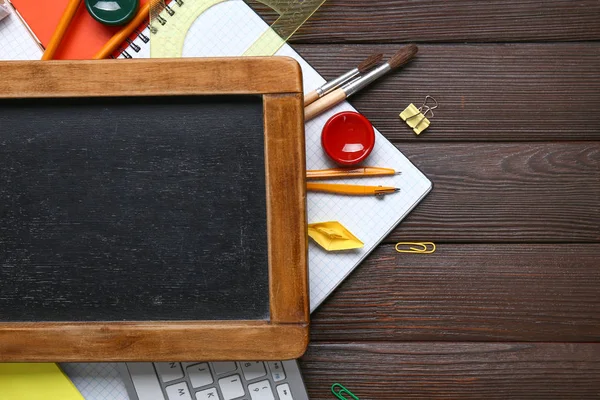 Set of school supplies with chalkboard and computer keyboard on wooden background — Stock Photo, Image