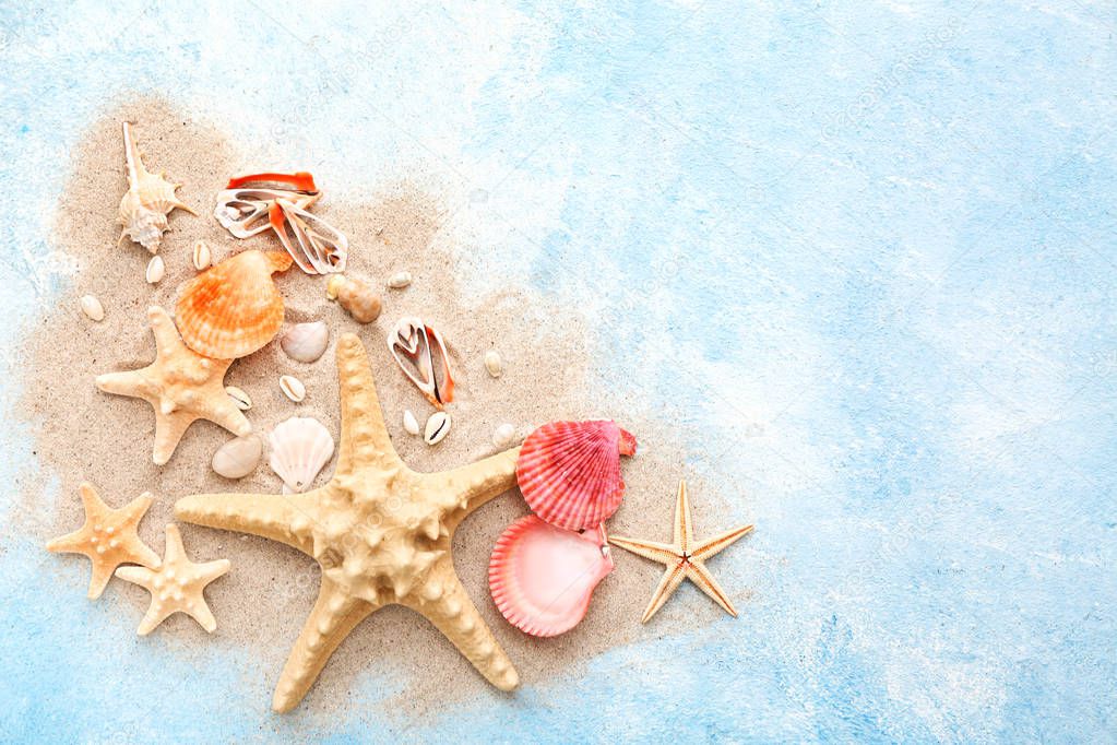 Beautiful sea shells, starfish and sand on color background