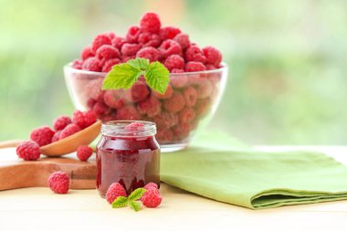 Ahşap masada çilek ile kavanozda Lezzetli ahududu reçeli