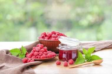 Ahşap masada çilek ile kavanozda Lezzetli ahududu reçeli