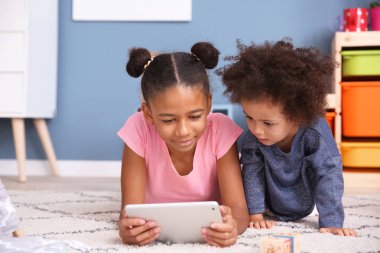 Tablet bilgisayar evde çizgi film izlerken sevimli Afrikalı-Amerikalı kız
