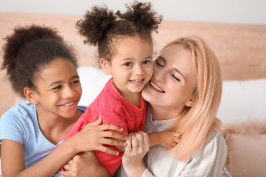Happy woman with her African-American daughters at home clipart