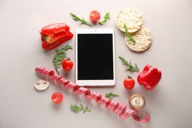 Taze ürünler ve gri arka plan üzerinde ölçüm bandı ile modern tablet bilgisayar