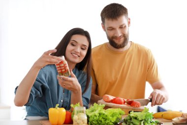 Genç çift mutfakta birlikte yemek pişiriyor.