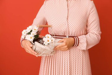 Kadın renkli arka planda lezzetli kiraz suyu ve çiçek şişeleri ile sepet tutan