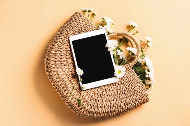 Renkli arka planda hasır çanta ve çiçekler ile modern tablet bilgisayar