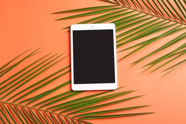Renkli arka planda tropikal yapraklar içeren modern tablet bilgisayar
