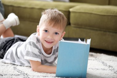 Evde kitap okuyan şirin bir çocuk.