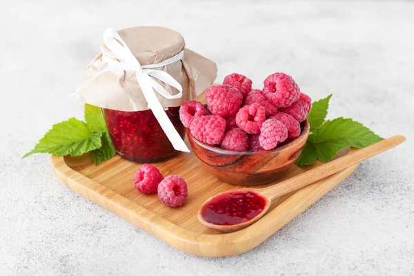 Вкусное малиновое варенье в банке с ягодами в миске на светлом фоне — стоковое фото