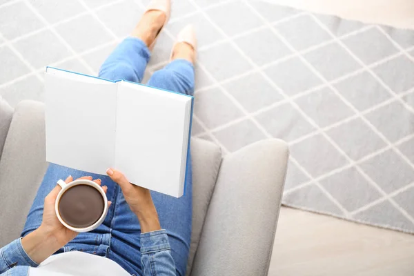 Mujer bebiendo café mientras lee libro en casa — Foto de Stock