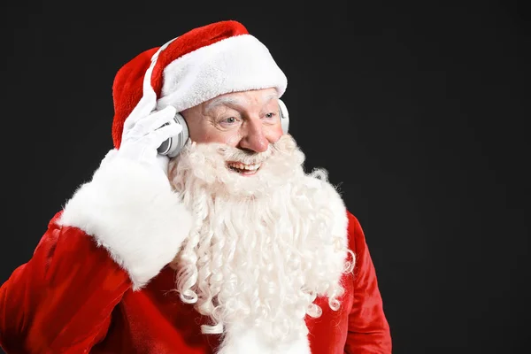 Portrait of Santa Claus listening to music on dark background — Stock Photo, Image