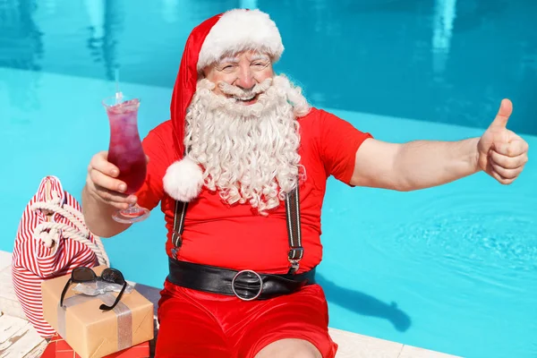 Santa Claus with cocktail near swimming pool at resort — Stock Photo, Image