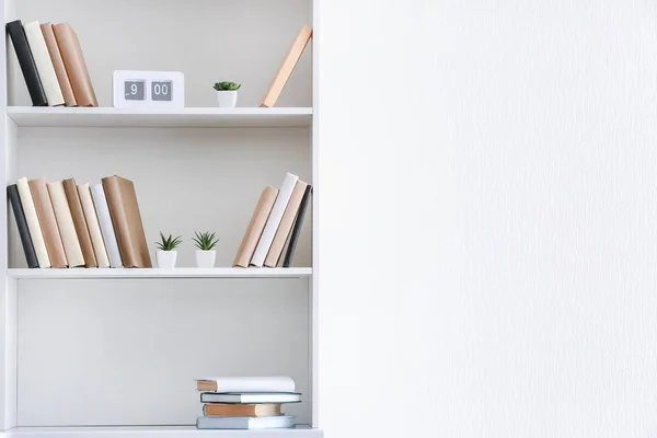 Unidad de estante con libros cerca de la pared blanca —  Fotos de Stock