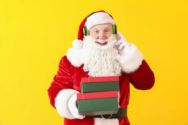 Retrato de Papai Noel com caixas de presente ouvindo música sobre fundo de cor — Fotografia de Stock